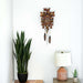 Wooden cuckoo clock hanging above potted plant and lamp in bedroom 