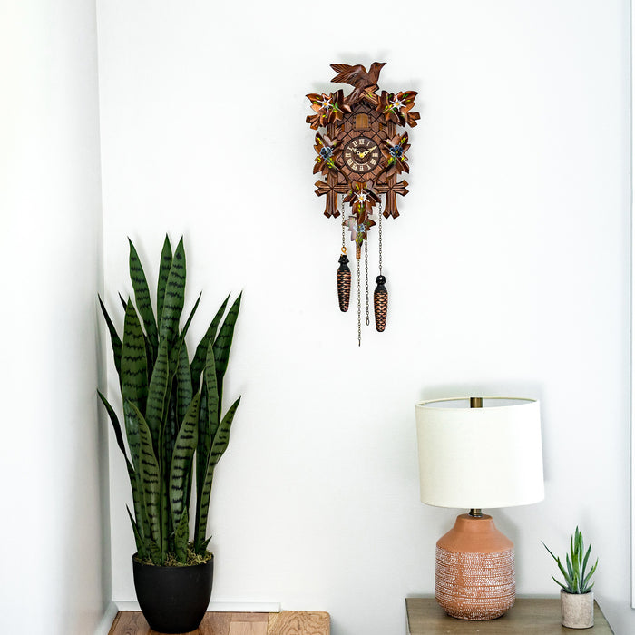 Wooden cuckoo clock hanging above potted plant and lamp in bedroom 