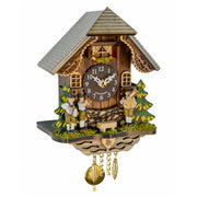 A traditional German cuckoo clock shaped like a mountain chalet with a gray shingled roof, carved wooden figures of German Oompah band, green and yellow pine trees, and brass hanging weights below.