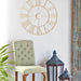 Decorative gold wall clock above a chair with a plant and lanterns in the foreground.