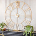 Large decorative wall clock with gold Roman numeral design on a white paneled wall.
