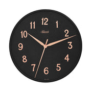 Wall clock with black face and gold numbers on white background.