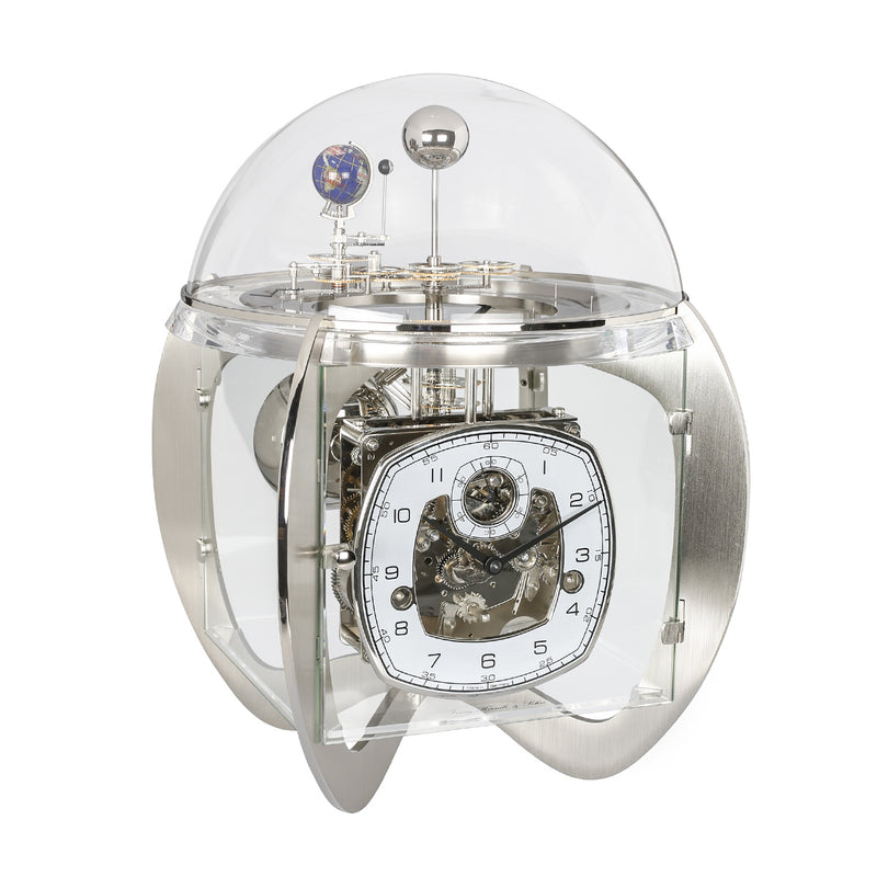 Silver astronomical clock with visible intricate movement and planet gears beneath glass dome on white background.