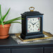 Decorative clock with floral design on dresser next to a potted plant