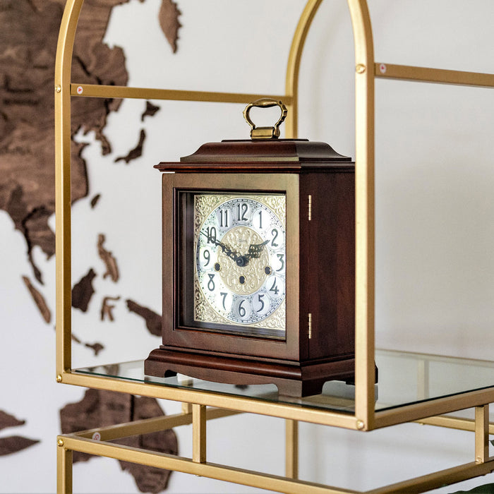 Wooden clock on a gold and glass shelf against a world map background