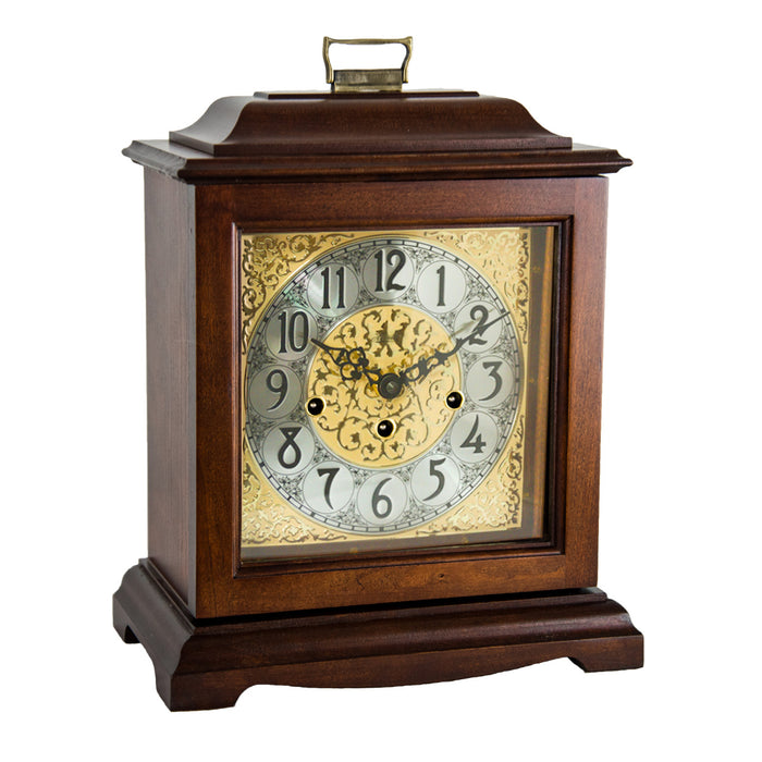 Cherry wood decorative clock with intricate design and holes on the face for winding on a white background