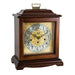 Cherry wood decorative clock with intricate design and holes on the face for winding on a white background