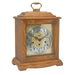 Dark oak wood decorative clock with intricate design and holes on the face for winding on a white background