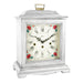 White decorative clock with floral design and holes on the face for winding on a white background