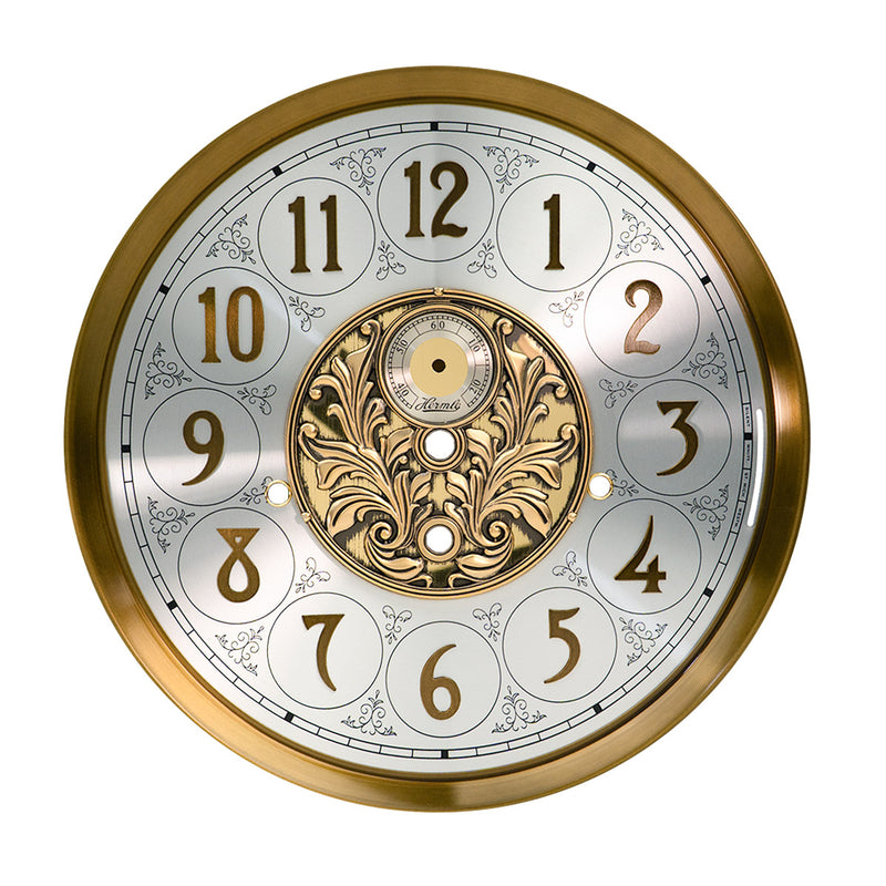 Brass and nickel clock face with ornate designs on white background.