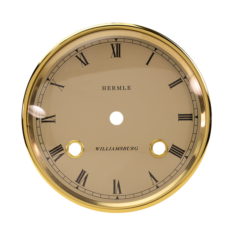 Brass rimmed dial with cream face and Roman Numerals on white background. 