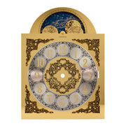 Brass clock face with intricate detail and moon dial with reflective finish on white background.