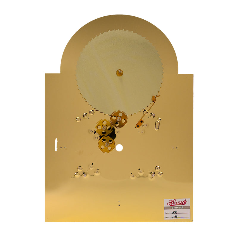 Rear view of brass clock face with visible gears and mounting points on white background.