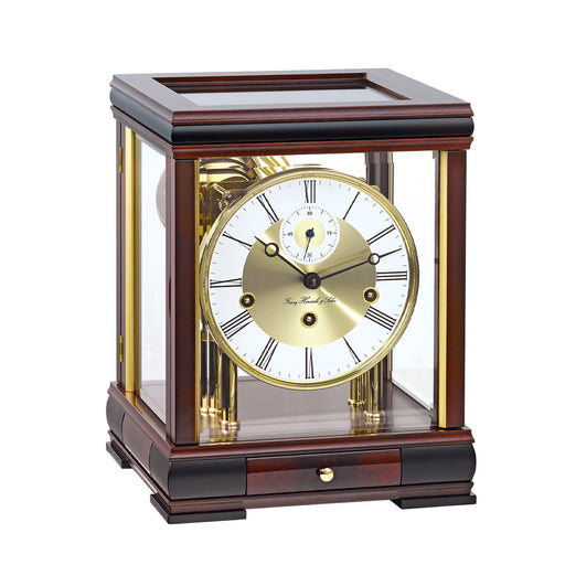 Dark mahogany wood mantel clock with brass face and glass sides on white background.