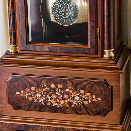Close up of ornate flower inlay on the base of a wooden grandfather clock