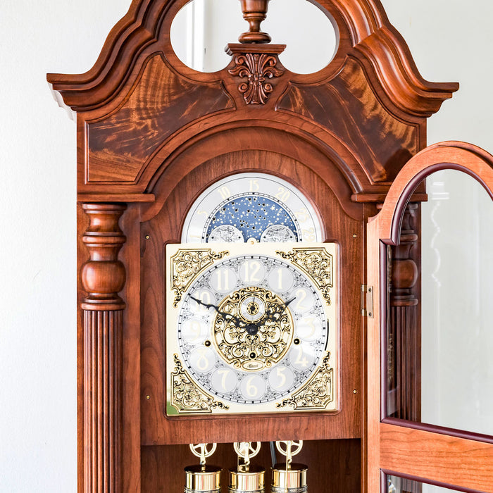 Ornate wooden grandfather clock with detailed face against white wall