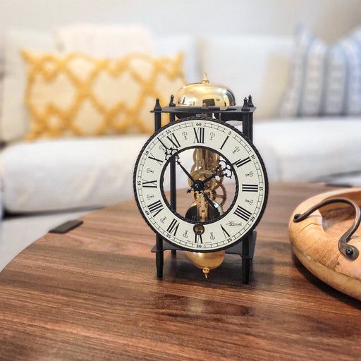 Decorative mantel clock with black frame and brass gears on wooden coffee table.