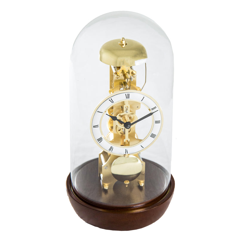Walnut Mechanical clock with glass dome and visible brass gears and roman numeral face on white background.