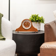 Light Cherry wood mantel clock with holes in the face for winding the mechanical movement inside on side table in living room