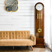 Walnut grandfather clock in front of white plank wall, next to beige couch 