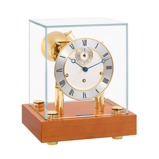 Walnut desk clock with glass case and silver clock face with brass highlights on white background