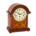 Wooden mantel clock with holes for winding the mechanical movement inside on white backdrop