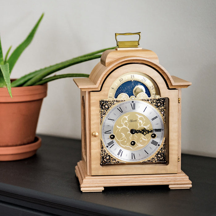 Light oak clock on black mantle with decorative plant in living room 