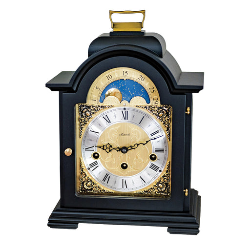 Black and brass mantel clock with roman numerals and ornate face on white background.