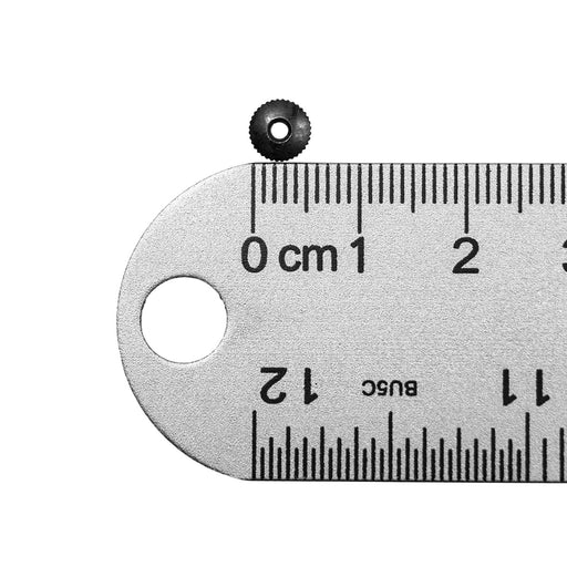 Small black hand nut next to ruler showing half centimeter measurement on white background.