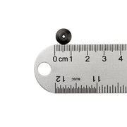 Black hand nut next to ruler showing one centimeter measurement on white background. 