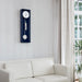 Blue wall clock hung above white couch in living room with plants on the side