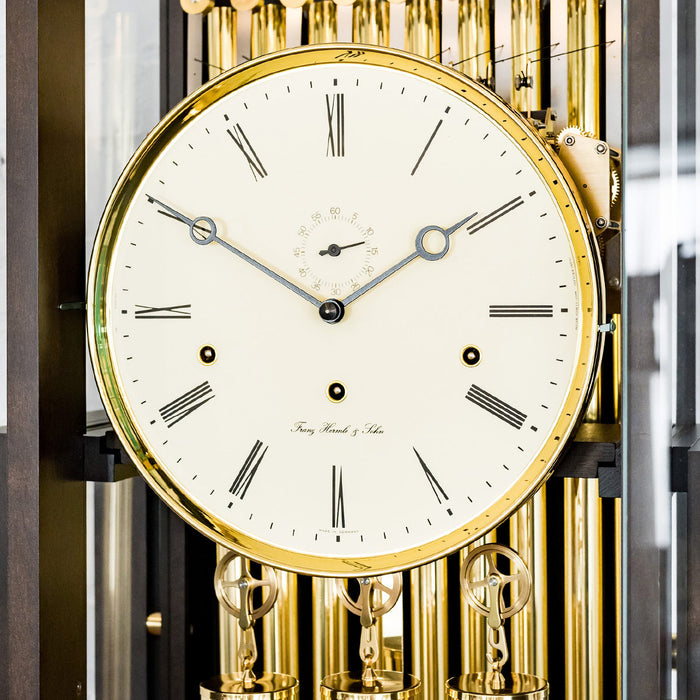 Close up of roman numeral clock face with brass highlights and seconds display