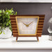 Retro Style wood desk clock with brass accents on white shelf with green plant nearby.