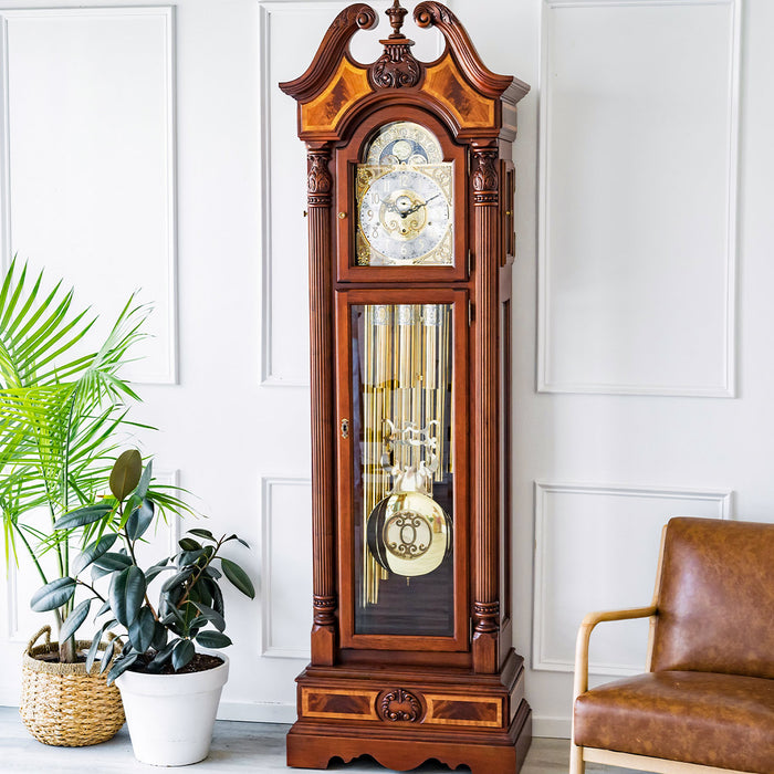 Wooden grandfather clock in a white room with green plants and a leather chair