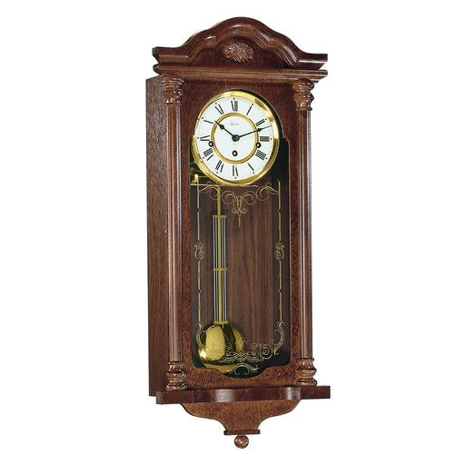 Intricate wooden wall clock with brass highlights and holes on the face for winding the mechanical movement inside