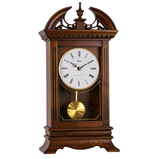 wooden mantel clock with decorative elements on top, and brass pendulum below.