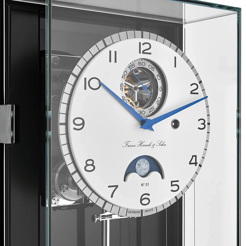 Luxury watch with intricate design and visible Franz Hermle and Sohn brand name in a clear display case.
