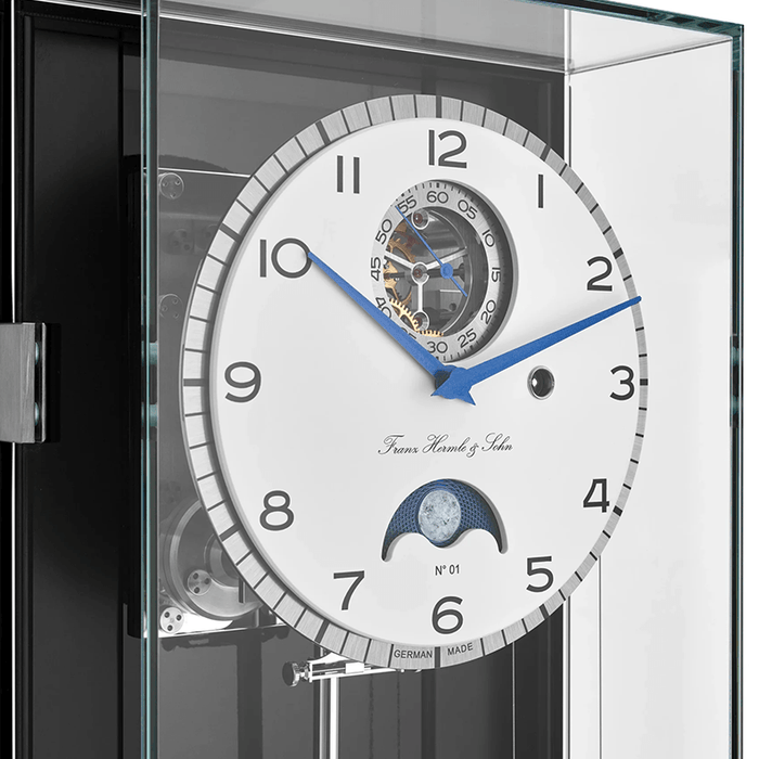 Luxury watch with intricate design and visible Franz Hermle and Sohn brand name in a clear display case.