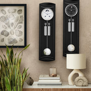 Mornington 2 German regulator clock (black) in living room scene with plant and lamp and framed seashell print.