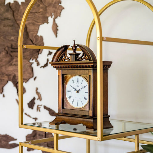 Decorative wooden clock on a glass shelf with a gold frame, against a world map background.