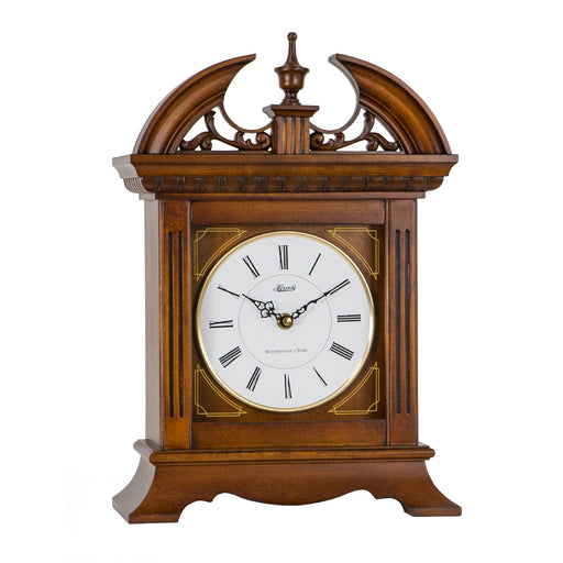 Wooden mantel clock with roman numeral face and thin brass highlights on white background.