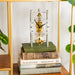 Silver and brass mechanical clock with glass face on stack of books