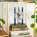 Blue and silver clock sitting on stack of books next to potted plants 