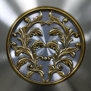 Up close of intricate brass detail on brushed nickel grandfather clock pendulum 