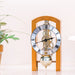 Light cherry mechanical clock on white table next to green plant