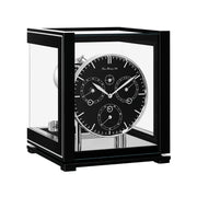 Black perpetual calendar clock with black face, silver highlights and glass panels on white background.