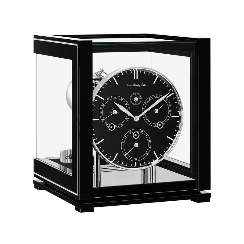 Black perpetual calendar clock with black face, silver highlights and glass panels on white background.