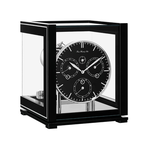 Black perpetual calendar clock with black face, silver highlights and glass panels on white background.