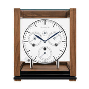 Front view of walnut perpetual calendar clock with silver highlights and glass panels on white background.