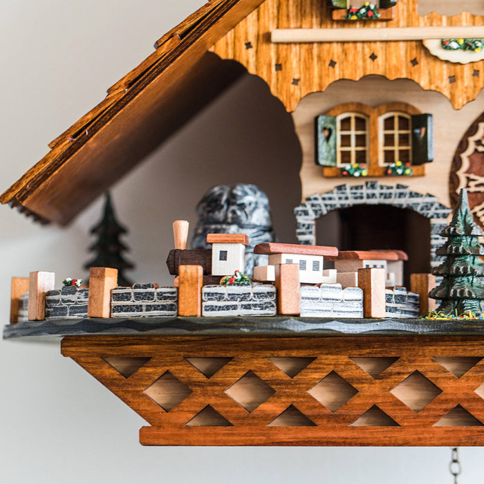 Up close view of small wooden train on detailed cuckoo clock